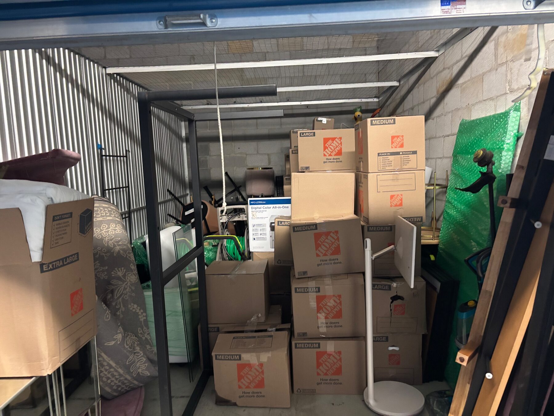 A storage unit packed with stacked moving boxes and furniture