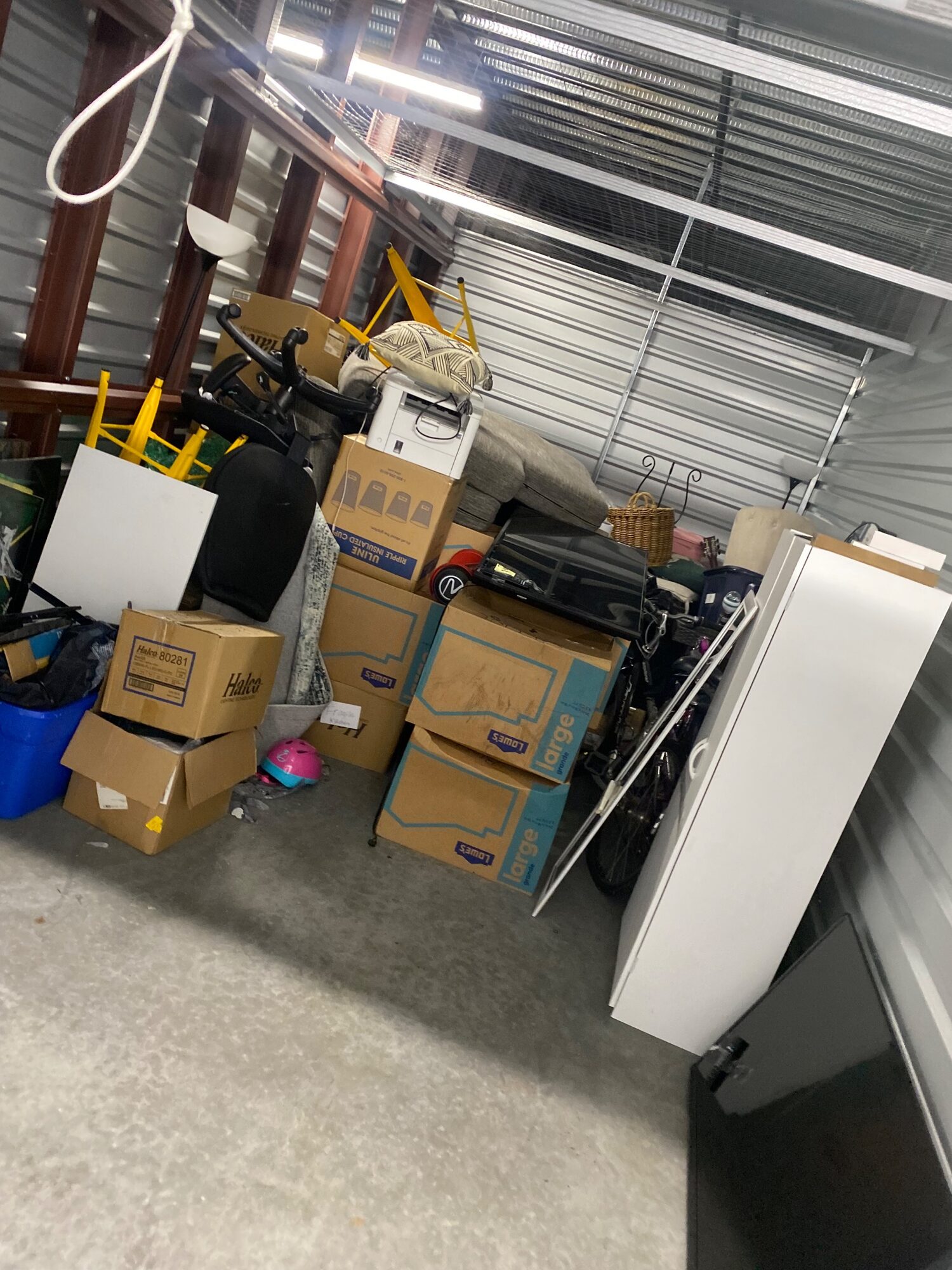A storage unit being cleared, boxes and household items stacked against the wall